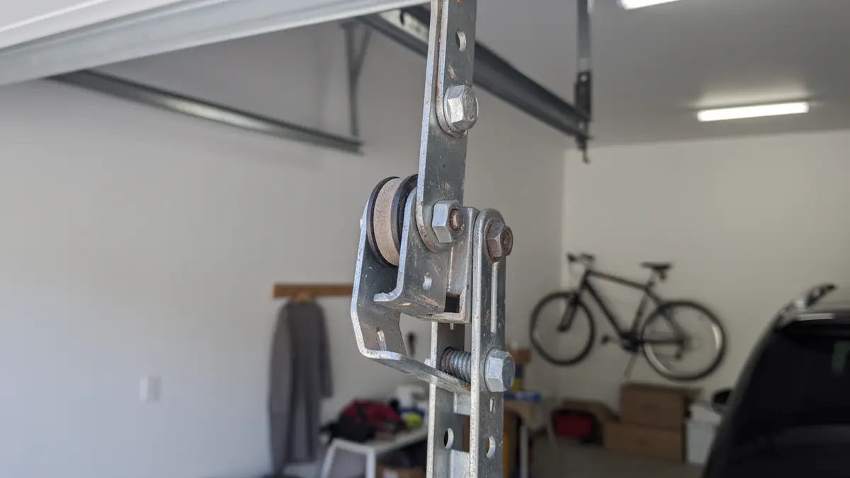 A close-up of a garage door opener trolley with a pulley and bolts.